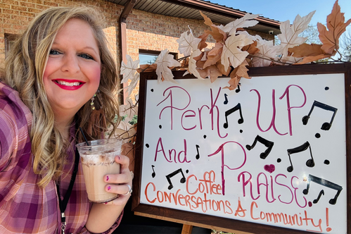 Coffee in the hand of a church member beside a sign that reads Perk Up & Praise Coffee & Conversations
