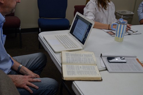 Sunday school go-ers with laptops, Bibles, and study notes open on the table they sit around