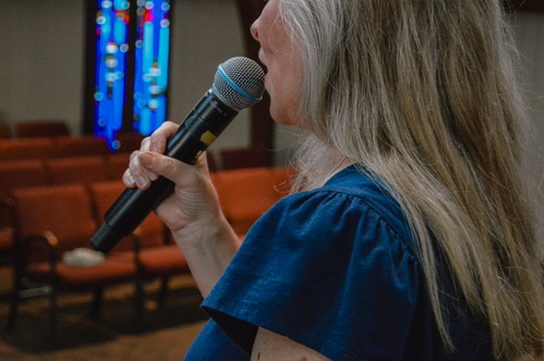 A woman sings into a microphone during Sunday morning worship service