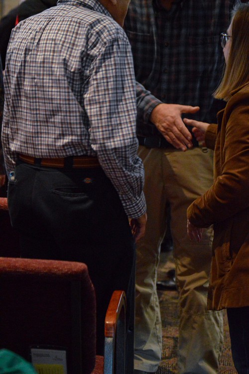 Church members greet and welcome one another with handshakes in the sanctuary.