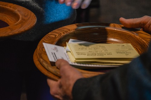 A close-up of a NABC offering plate stacked with giving envelopes
