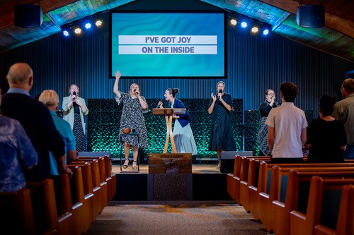 kids smiling and pointing to the left at something not shown on the image