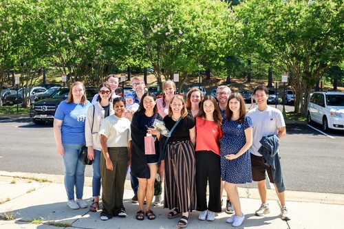 Group of smiling young adults sitting outdoors, enjoying fellowship at Restoration City Church.