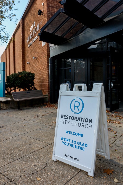 Smiling woman warmly greets another attendee during a Sunday service at Restoration City Church in Arlington, VA.